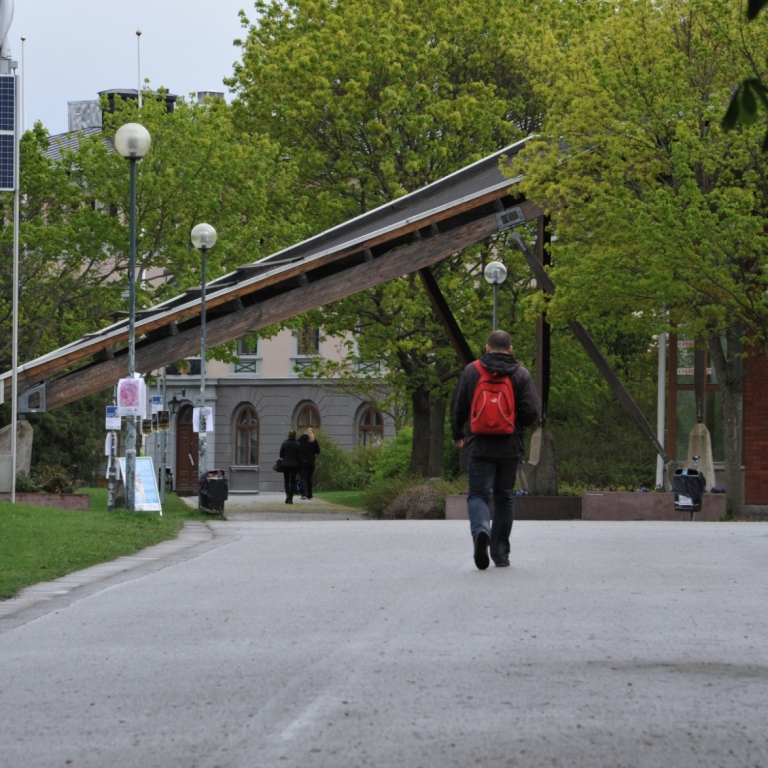 En person med röd ryggsäck går till Stockholms universitet från tunnelbanan