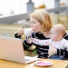 Blond kvinna med baby sitter vid en dator. Foto: Maria_Sbytova/Mostphotos