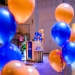 Orangea och blåa ballonger i en stor sal framför en talarstol med Stockholmsuniversitets logga på 