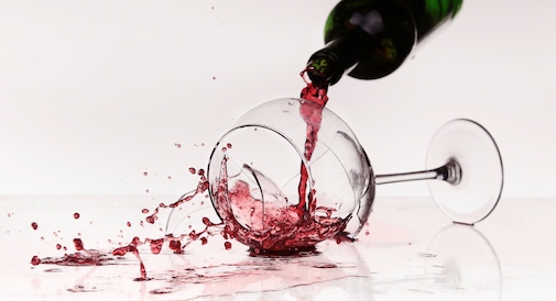 En flaska med rött vin och ett trasigt vinglas