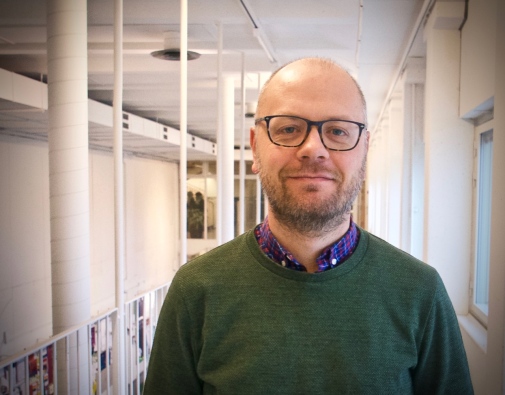 Professor Erik Lindqvist står i en korridor på Stockholm universitet