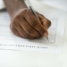 A dark-skinned hand writing a job application
