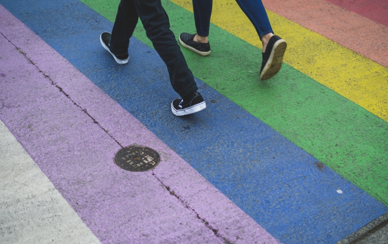Two people walking on a zebracxrossing in the rainbow colors
